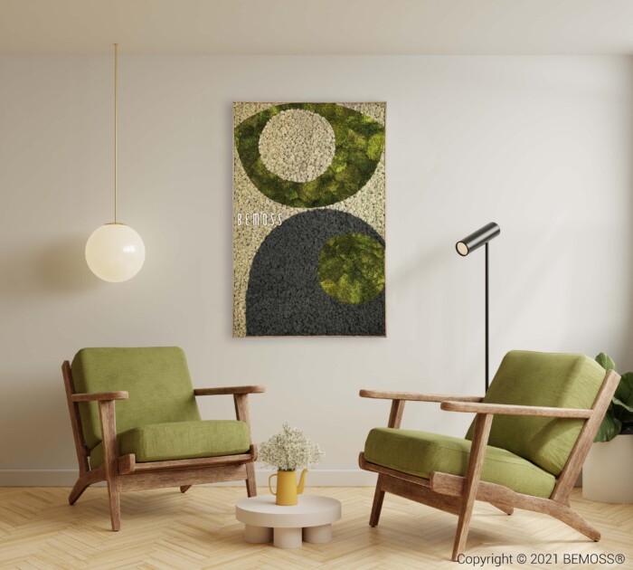 Een moderne woonkamer is voorzien van twee groene fauteuils met houten frame, een ronde witte bijzettafel met een potplant en een zwarte vloerlamp. Aan de lichtgekleurde muur hangt een Earth Jerte in groen, grijs en beige. Aan het plafond hangt een bolvormige hanglamp.