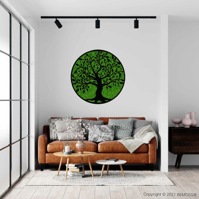 Een moderne woonkamer met een bruinleren bank versierd met diverse grijze en witte kussens en een deken. Boven de bank hangt een groot BEMOSS moschilderij-kunstwerk, dat een vleugje natuur toevoegt. De kamer is voorzien van een houten salontafel, decoratieve voorwerpen en railverlichting aan het plafond.