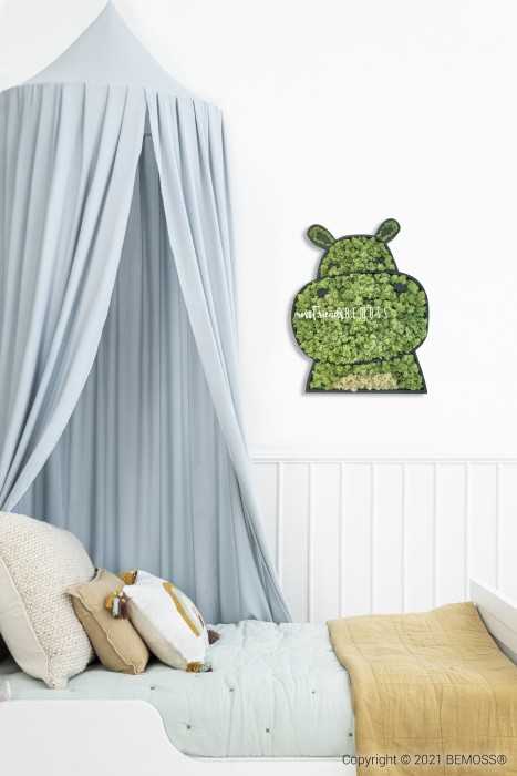 Een gezellige kinderkamer met een wit bed met kleurrijke kussens en een lichtgele deken. Boven het bed hangt een grijs hemeltje. Aan de muur hangt een decoratieve BEMOSS-mosschilderij in de vorm van een nijlpaard, waarmee een natuurelement wordt toegevoegd. De kamer heeft een rustgevende en uitnodigende sfeer.