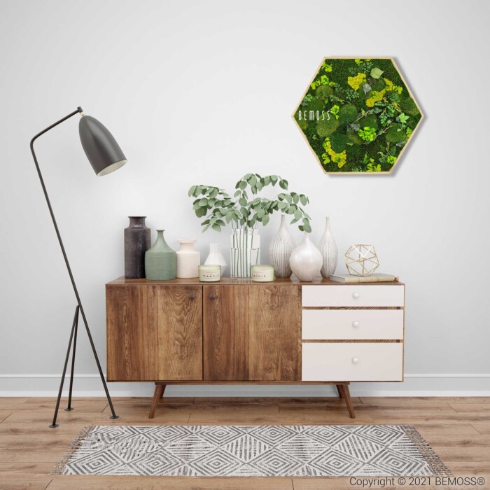 Een moderne woonkamer is voorzien van een houten dressoir met witte laden, een verscheidenheid aan decoratieve vazen en een potplant. Daarboven hangt een zeshoekige Moshexagon PLANTEN Mesia Lime. Een hoge vloerlamp en een geometrisch vloerkleed voegen stijl toe aan de neutraal getinte ruimte.