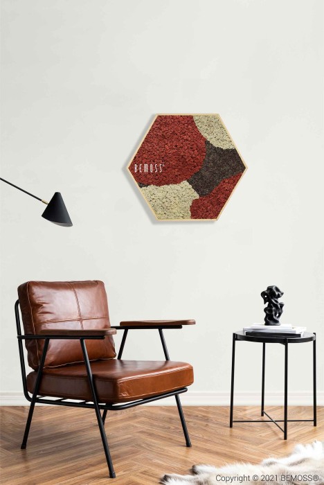 Een moderne woonkamer is voorzien van een bruinleren fauteuil en een klein zwart bijzettafeltje met een beeldhouwwerk. Boven de stoel bevindt zich een zeshoekig kunstwerk aan de muur met een gestructureerd, veelkleurig patroon. Als aanvulling op het minimalistische ontwerp beschikt de kamer over een zwarte vloerlamp, een ruig wit tapijt en een opvallende Moshexagon BEMOSS® ORTHO SIENNA.