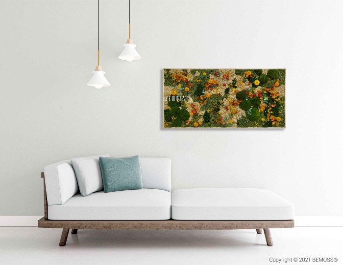 Een minimalistische woonkamer is voorzien van een witte bank met houten poten, versierd met groene en witte kussens. Daarboven is een kleurrijk abstract schilderij op een witte muur gemonteerd naast een Mosschilderij PLANTEN Lomo. Aan het plafond hangen twee hanglampen. Copyright © 2021 BEMOSS® wordt rechtsonder weergegeven.