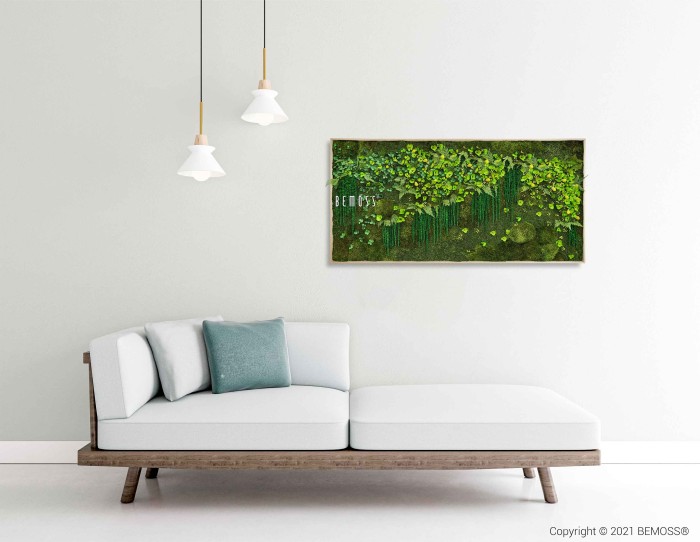 Een moderne woonkamer met een witte L-vormige bank en groene sierkussens. Aan het plafond hangen twee hanglampen. Aan de muur hangt een Mosschilderij PLANTEN Lomo met weelderige groene planten, die een verfrissend tintje geven aan de minimalistische ruimte.